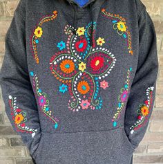 This colorful sweatshirt is perfect to keep warm, comfortable, and stylish during the cold winter months. They have hand embroidered details on both sleeves, front center, and on the hoodie. This sweatshirt is hand embroidered by Mexican Artisans and each can take up to a week for one person to finish!  Each sweater is 50% cotton/50% polyester.  Please choose a size in the drop down menu. You will receive a sweatshirt with the same pattern as the picture, however, the colors may differ as they a Embroidered Hooded Sweatshirt For Winter, Hooded Embroidered Sweatshirt For Winter, Casual Multicolor Embroidered Sweater, Casual Embroidered Winter Sweater, Hooded Winter Sweatshirt With Embroidered Graphics, Casual Embroidered Sweater For Winter, Winter Hooded Sweatshirt With Embroidered Graphics, Winter Sweater With Multicolor Embroidery And Long Sleeves, Winter Long Sleeve Sweater With Multicolor Embroidery