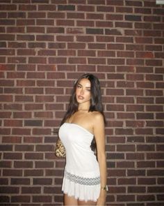 a woman standing in front of a brick wall