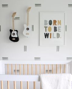 a white crib with two guitars hanging on the wall