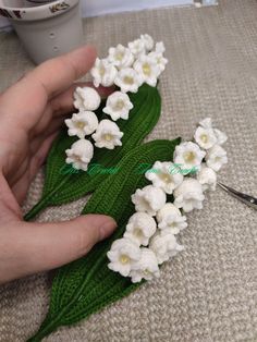 a person is holding some white flowers in their hand on the table next to a pair of scissors