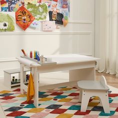 a child's desk and chair in a room with art on the wall behind it