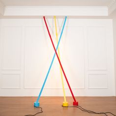 two plastic poles with wires attached to them on the floor in front of a white wall