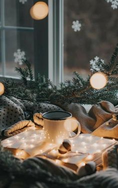 a cup of coffee sitting on top of a table next to a window covered in snowflakes