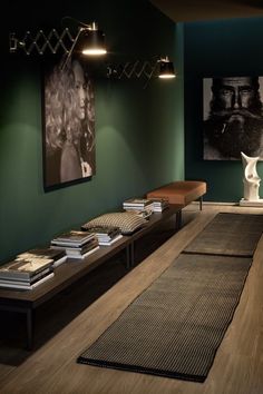 a room with green walls and wooden flooring is lit by two pendant lights that hang from the ceiling