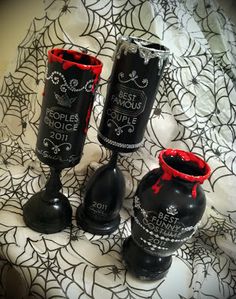 three black vases sitting on top of a bed covered in spider web and red ribbon