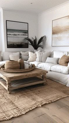 a living room with white couches and pillows on top of the rug in front of a large painting