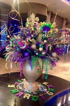 a vase filled with lots of purple and green decorations on top of a table in a room