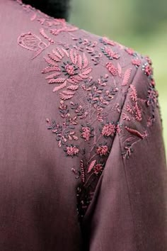 the back of a woman's jacket with embroidered flowers on it and an embellishment