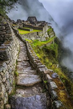 the stairs lead up to an old stone building on top of a mountain with fog in the background