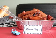 hot dogs and buns in tinfoil containers on a table with checkered tablecloth