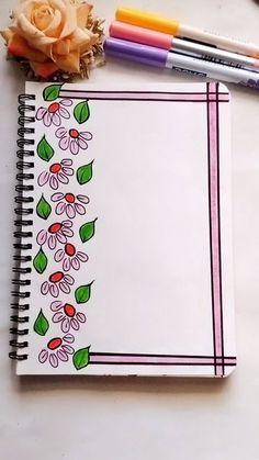 an open notebook with flowers and crayons next to it