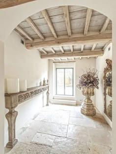 an archway leading to a living room filled with furniture and flowers in vases on either side of the doorway