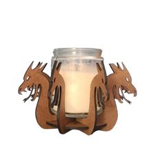 a candle that is sitting in front of a glass jar with wood decorations on it