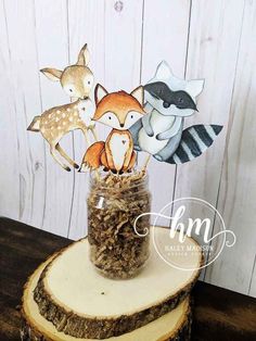 a jar filled with paper animals sitting on top of a tree stump