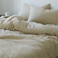 an unmade bed with white sheets and pillows