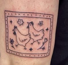 a couple of chickens in a frame tattoo on the right side of the calf's leg