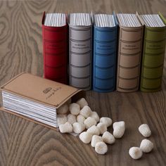 several books and some small white balls on a wooden table with a book in the middle