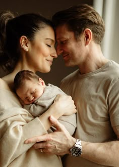 a man and woman holding a baby in their arms