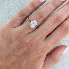 a woman's hand with a diamond ring on her finger and pink manicured nails