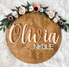 a wooden sign with flowers and leaves on it that says, olvia nikolae