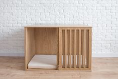 a wooden crib sitting on top of a hard wood floor next to a white brick wall