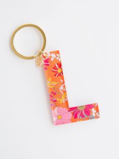 the letter l is decorated with flowers and gold metal keychain on a white background