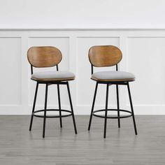 two stools with wooden backrests and white upholstered seat, against a wall