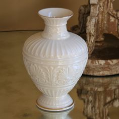 a white vase sitting on top of a glass table