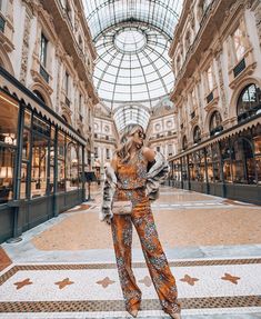 a woman standing in the middle of a shopping mall wearing an orange floral jumpsuit