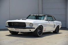 an old white mustang sitting in front of a garage door