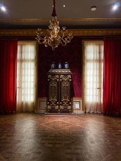 a fancy room with red curtains and a gold chandelier hanging from the ceiling