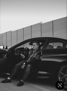 a man sitting in the driver's seat of a car next to another car