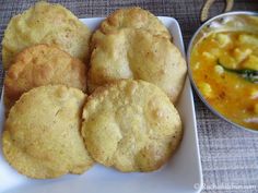 some food is sitting on a plate next to a bowl of soup and a spoon