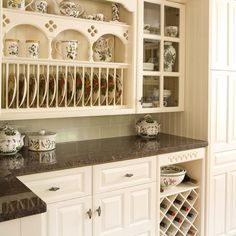 a kitchen filled with lots of white cupboards and counter top covered in china dishes