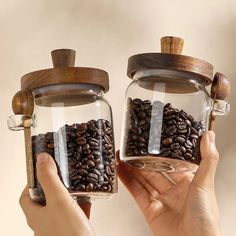 two hands holding glass jars filled with coffee beans