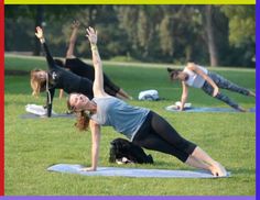 a group of people doing yoga in the park with their hands up and legs apart