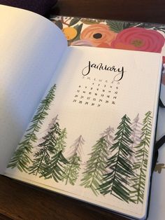 an open planner with pine trees on it and the word january written in cursive writing