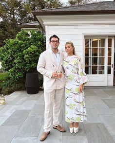 a man and woman standing in front of a house