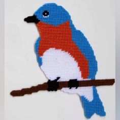 a cross stitch bird sitting on a branch