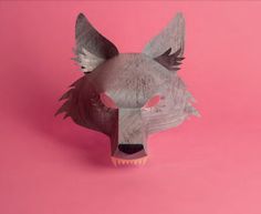 an origami wolf head on a pink background