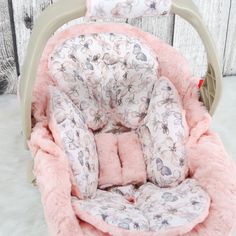 a baby's car seat cover with pink flowers and hearts on it, sitting in the snow