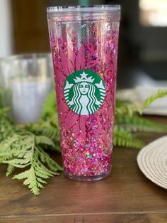 a pink starbucks cup sitting on top of a wooden table