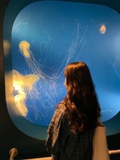 a woman looking at jelly fish in an aquarium