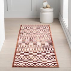 a white toilet sitting on top of a wooden floor next to a rug in a bathroom