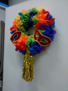 a colorful wreath hanging on the wall next to a door with a mask on it