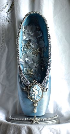 a blue shoe with silver decorations on the bottom and sides sitting on a white cloth