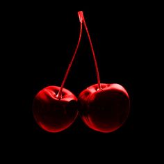 two red cherries hanging on a black background