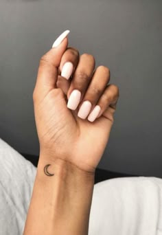 a woman's hand with a small crescent tattoo on her left wrist, and the moon