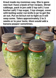 four jars filled with green cabbage sitting on top of a counter next to each other