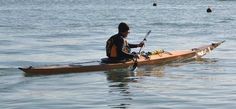 a man sitting on top of a kayak in the middle of the ocean with two oars